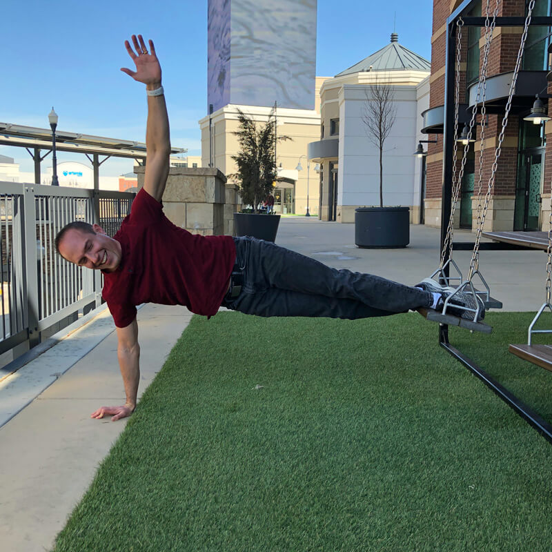 David doing a side-plank off a swing-set seat.