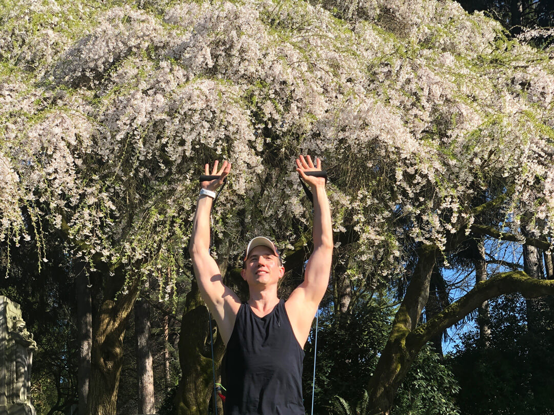 David working out under a cherry tree in blossom.